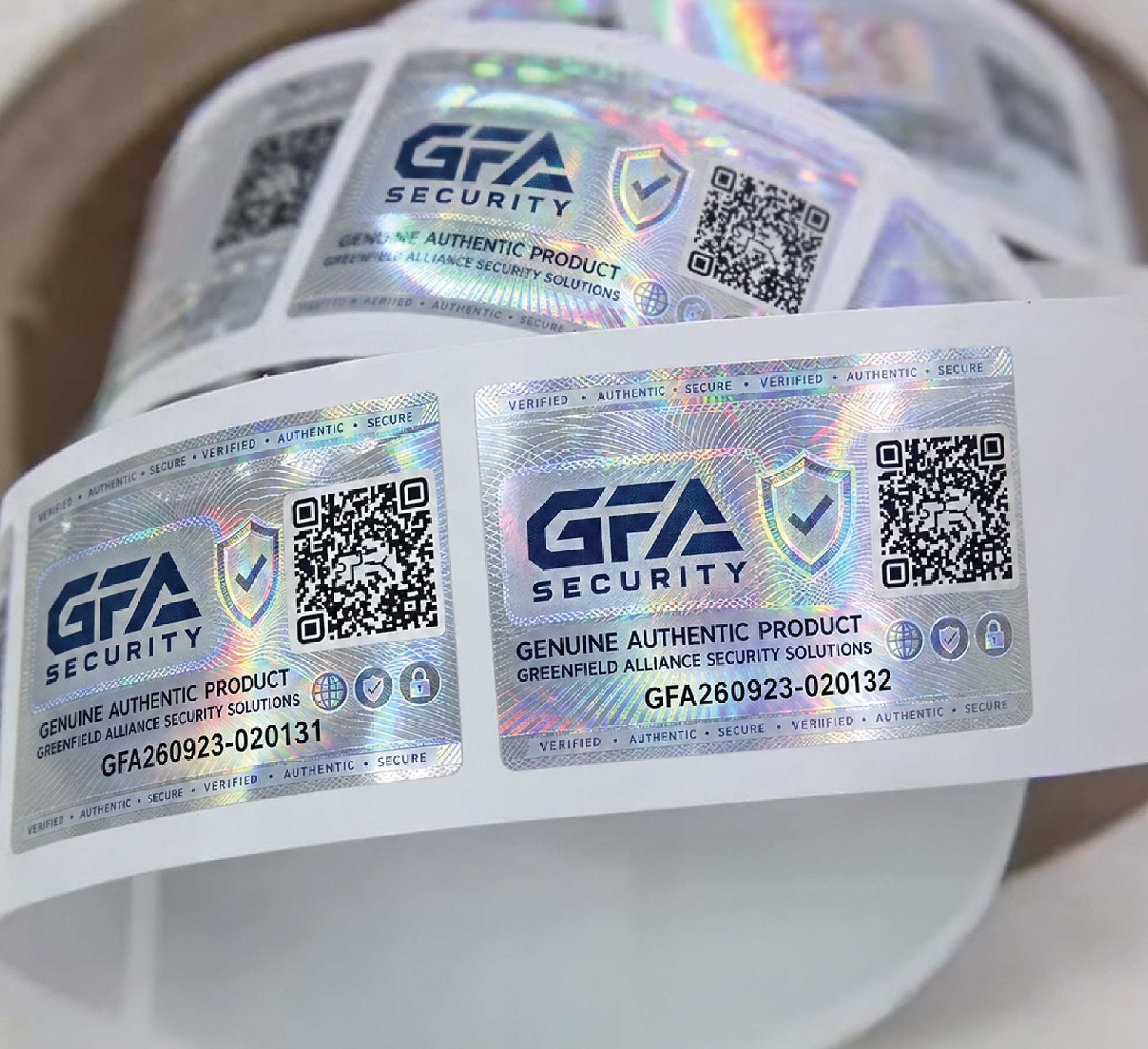 Roll of silver holographic GFA security labels with QR codes, shield graphics and printed serial numbers.